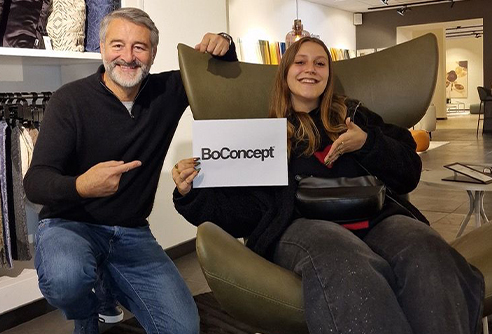 Noée, avec Laurent Balayer de chez BoConcept, assise sur le fauteuil qu’elle a remporté.